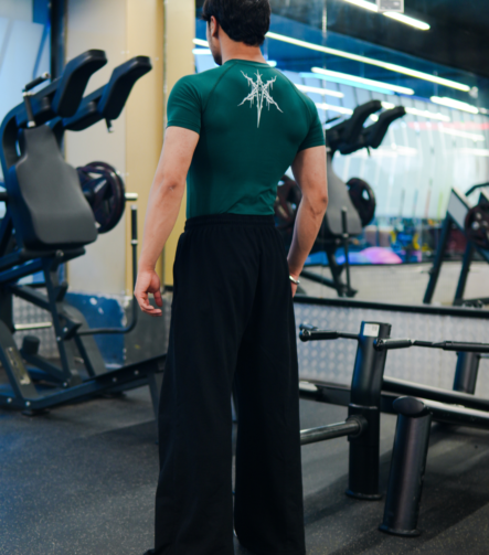 Young Goat green compression t-shirt full back view standing in gym — men's gym wear