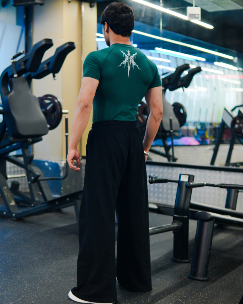 Young Goat green compression t-shirt full back view standing in gym — men's gym wear